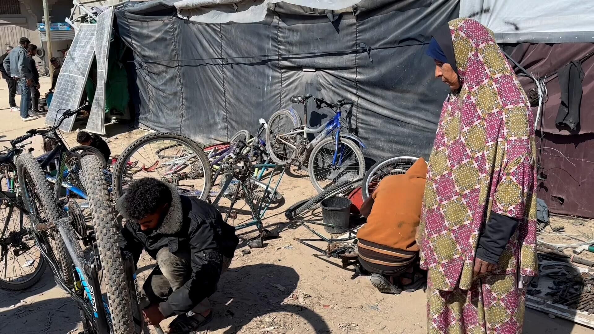 عائلة نازحة تحول خيمتها إلى مكان لتصليح الدرجات الهوائية في دير البلح وسط قطاع غزة... صور وفيديو