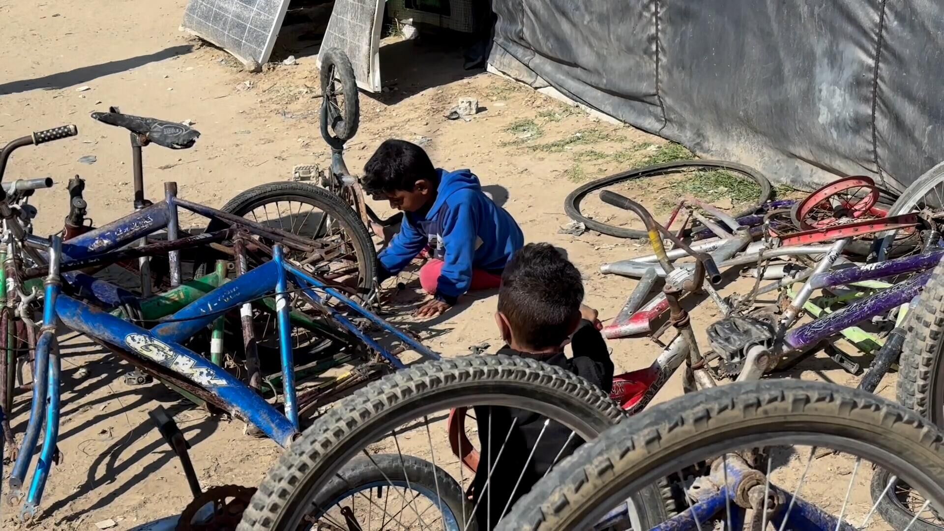 عائلة نازحة تحول خيمتها إلى مكان لتصليح الدرجات الهوائية في دير البلح وسط قطاع غزة... صور وفيديو