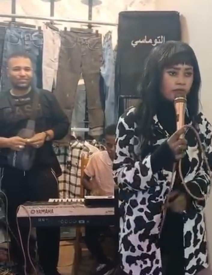 شاهد بالصورة والفيديو.. مطربة سودانية تغني داخل محل “بناطلين” وملبوسات رجالية بالقاهرة والجمهور يسخر: (نحنا نبكي والنور الجيلاني برضو يبكي)