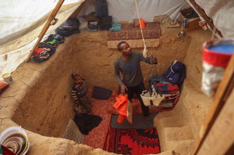 بالصور فلسطيني يحفر خندقا في خيمته لحماية أطفاله من البرد والقصف