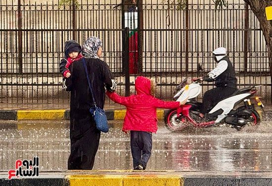 راجل من يومه.. طفل يوقف الطريق لعبور والدته وسط الأمطار الغزيزة.. صور