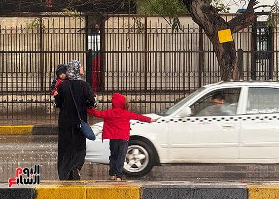 راجل من يومه.. طفل يوقف الطريق لعبور والدته وسط الأمطار الغزيزة.. صور
