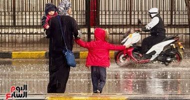 راجل من يومه.. طفل يوقف الطريق لعبور والدته وسط الأمطار الغزيزة.. صور