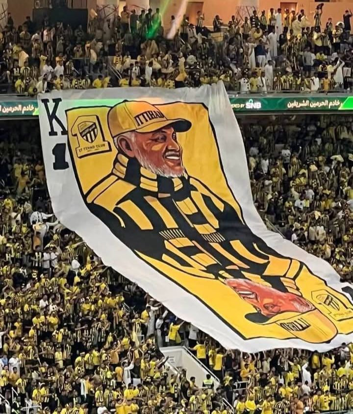 شاهد بالصور.. خلال نهائي كأس الملك.. جماهير الإتحاد السعودي تكرم الإداري السوداني العم كمال الذي خدم النادي لأكثر من 40 عام وترفع صورته بالمدرجات في “تيفو” عالمي