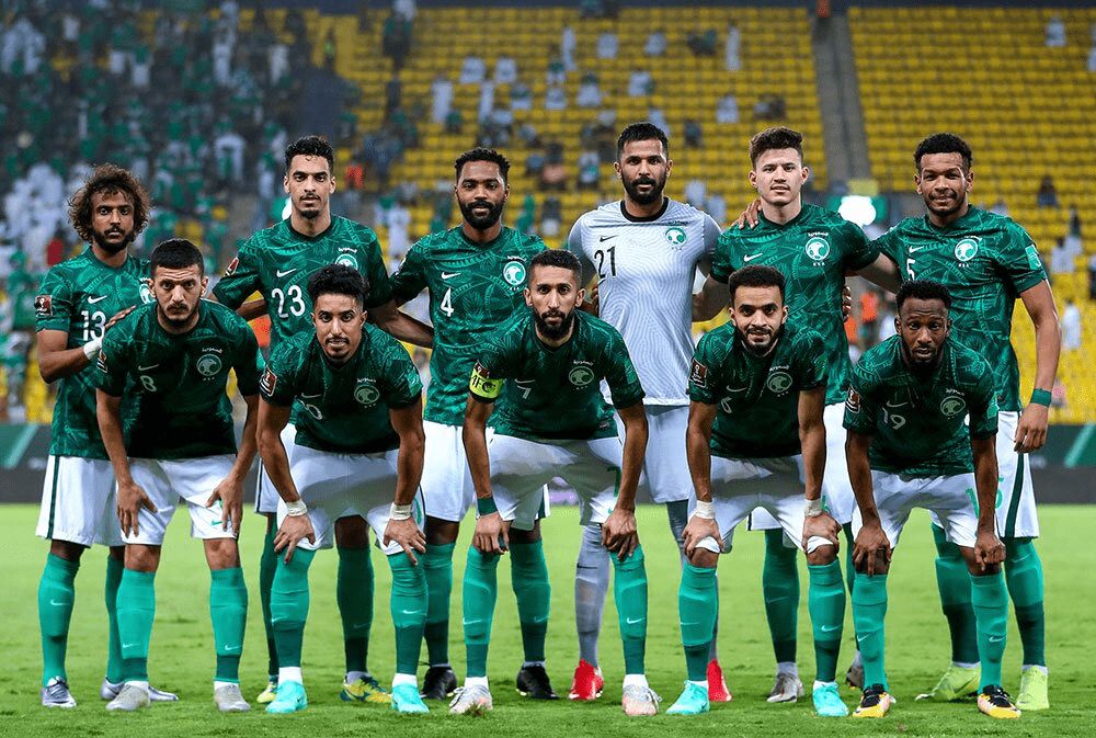 المنتخب السعودي لكرة القدم بلباسه الأخضر، يقف في أرض الملعب مستعداً لالتقاط صورة جماعية.