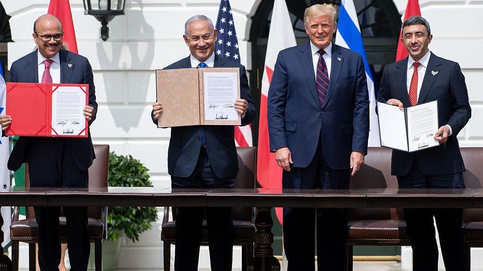 من اليمين إلى اليسار: وزير خارجية الإمارات عبد الله بن زايد آل نهيان، الرئيس الأمريكي دونالد ترامب، رئيس الوزراء الإسرائيلي بنيامين نتنياهو ووزير الخارجية البحريني عبد اللطيف الزياني يقفون مبتسمين في البيت الأبيض في أعقاب توقيع الاتفاقيات الإبراهيمية، وقد حمل كل من الوزير الإمارات والوزير البحريني ونتنياهو نسخة من الاتفاقية
