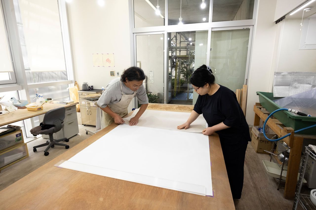 تتطلب عملية ضبط الورق وتثبيته وجود زوجين من الأيادي لضمان الدقة. (© كاواموتو سايّا)