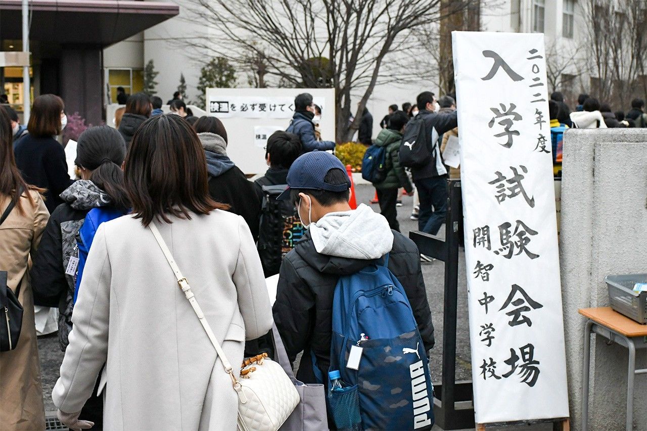 مشهد الطلاب المتقدمون لامتحان القبول في المرحلة الإعدادية، يوم 10 يناير/ كانون الثاني 2022، اثناء دخولهم إلى حرم كايتشي في مدينة سايتاما برفقة أولياء أمورهم. (© صحيفة سايتاما شيمبون)