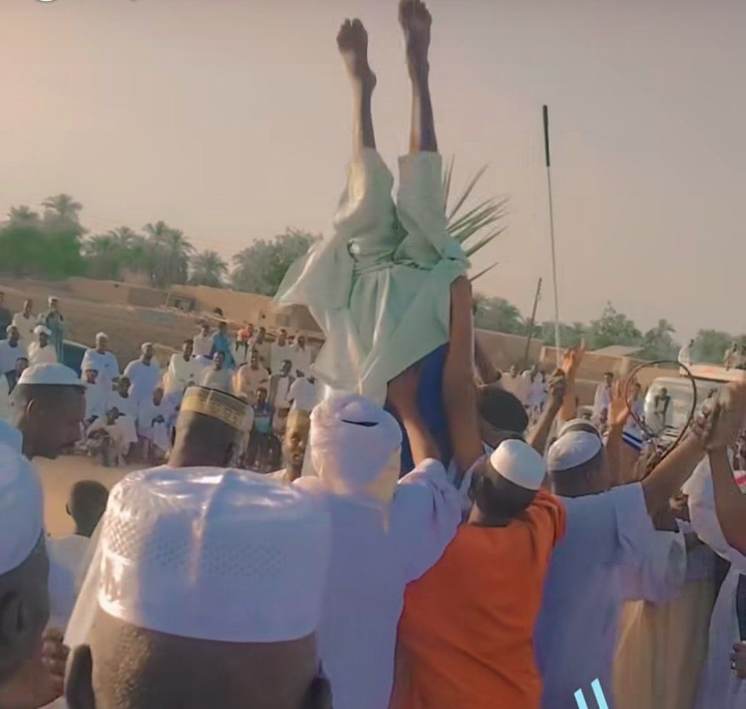 شاهد بالصورة والفيديو.. رجل سوداني يُدخل نفسه داخل “برميل” تفاعلاً مع أغنيات “الطمبور” والحاضرون يحملونه ويطوفون به ساحة الحفل