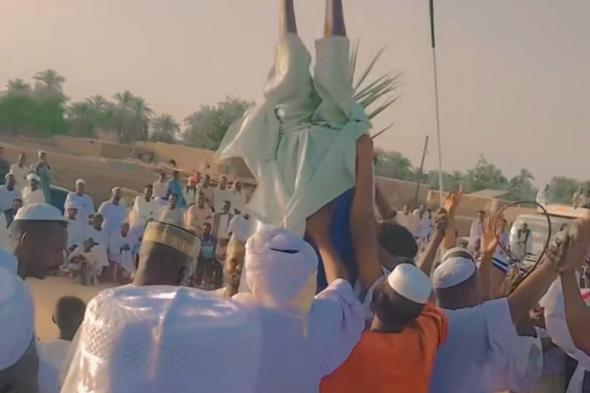 شاهد بالصورة والفيديو.. رجل سوداني يُدخل نفسه داخل “برميل” تفاعلاً مع أغنيات “الطمبور” والحاضرون يحملونه ويطوفون به ساحة الحفل